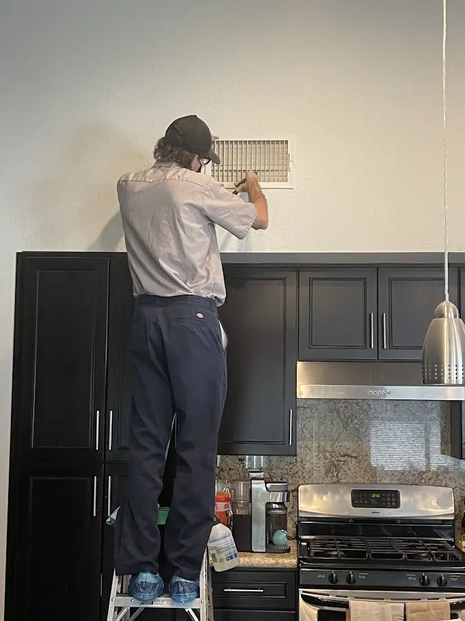 Technician inspecting an air vent during HVAC service in Glasgow